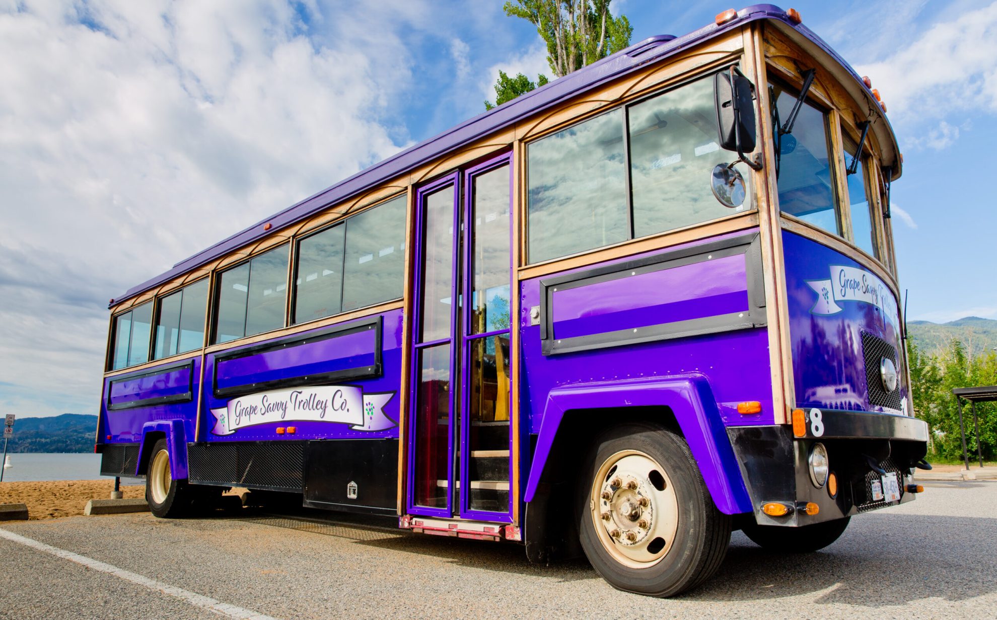 Grape Savvy Trolley Tours bus parked near the beach in Penticton