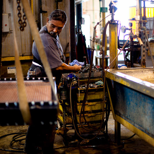 Top heat exchange manufacturer: A JB Radiator Specialties employee looking at a piece of equipment.